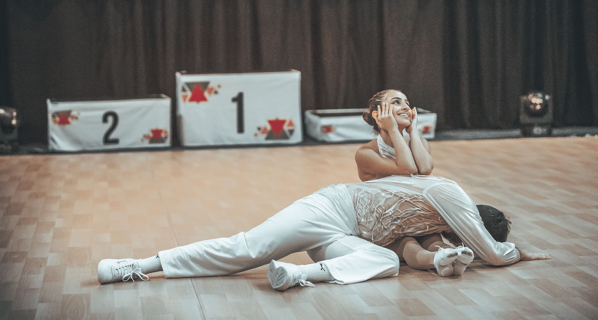 Couple de danseurs en blanc, en pose finale devant le podium